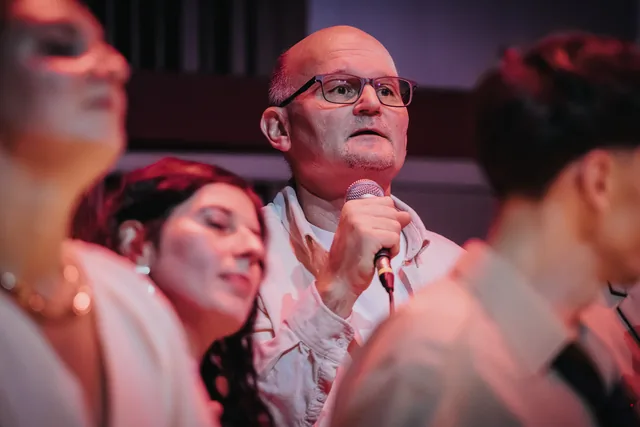 Chórzysta w okularach klaszczący podczas występu.