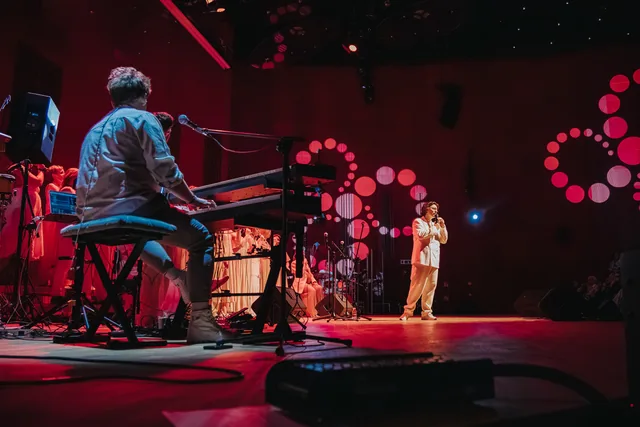 Instrumenty klawiszowe na pierwszym planie i dyrygent w głębi sceny.